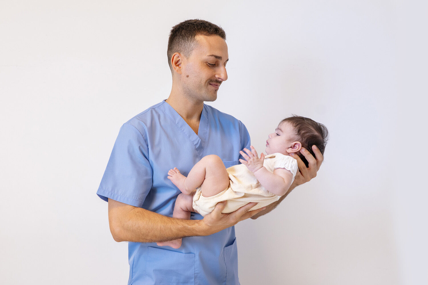 Mamma che tiene in braccio il suo neonato durante una delicata seduta di osteopatia pediatrica